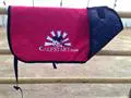 A red and blue saddle bag sitting on top of a fence.